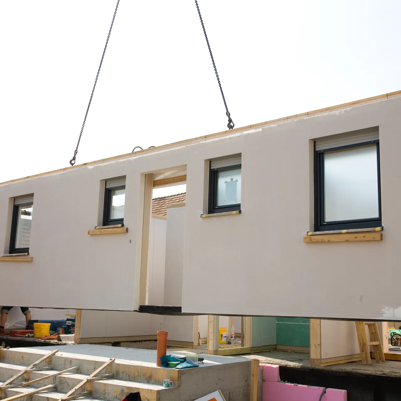 A wall of a new manufactured home on a crane being installed